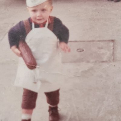© Schober GmbH Bub mit Schürze und einer Stange Wurst