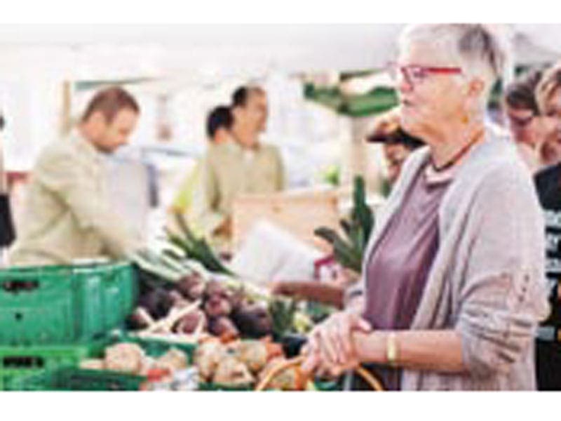 Frau kauft am Markt Gemüse