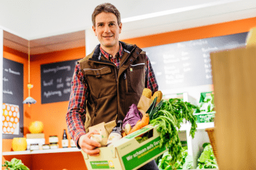 Biobauer mit Produkten im Einkaufskorb.