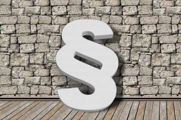 Weißes Paragraph-Symbol vor Ziegelmauer und auf Dielenboden